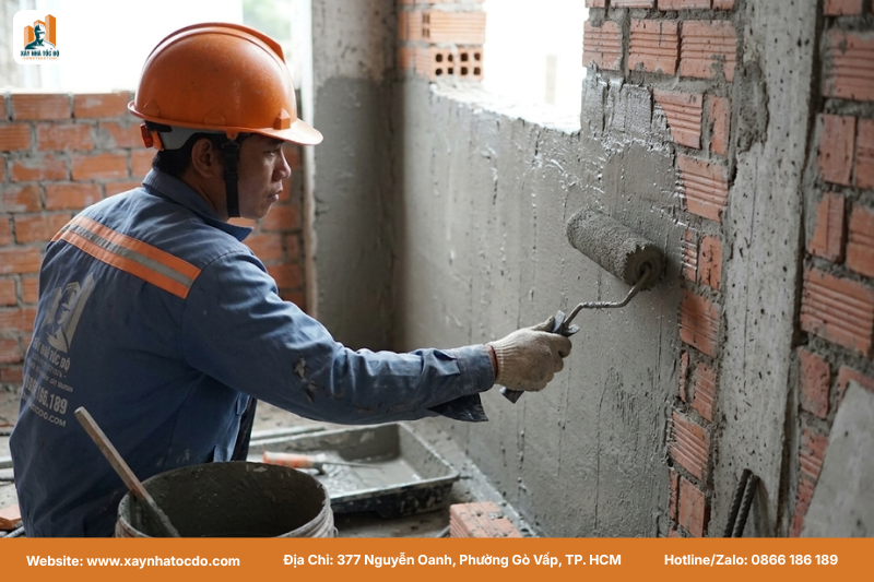 Thợ thi công quét lớp chống thấm gốc xi măng trong nhà vệ sinh, một bước quan trọng trong việc so sánh kỹ thuật chống thấm thực tế.