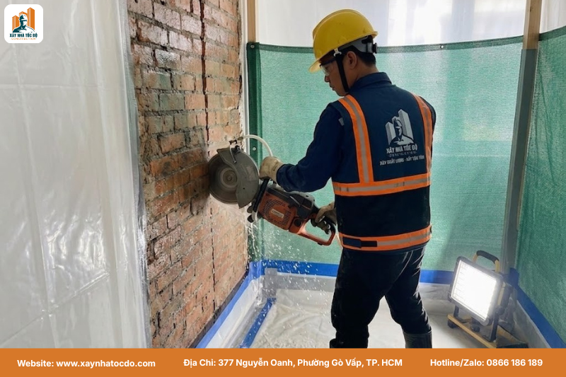 Công nhân sử dụng máy cắt bê tông bằng nước trong quá trình thi công cải tạo nhà đang ở.